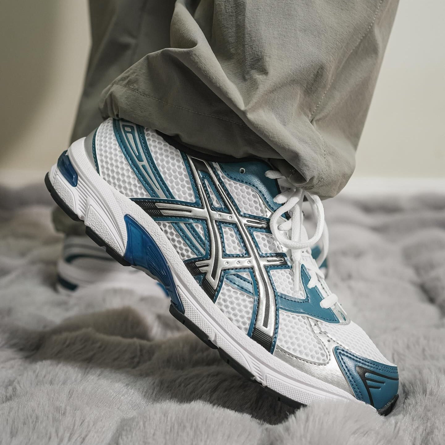 ASICS Gel-1130 White Restful Teal on foot medial side close-up with grey trousers