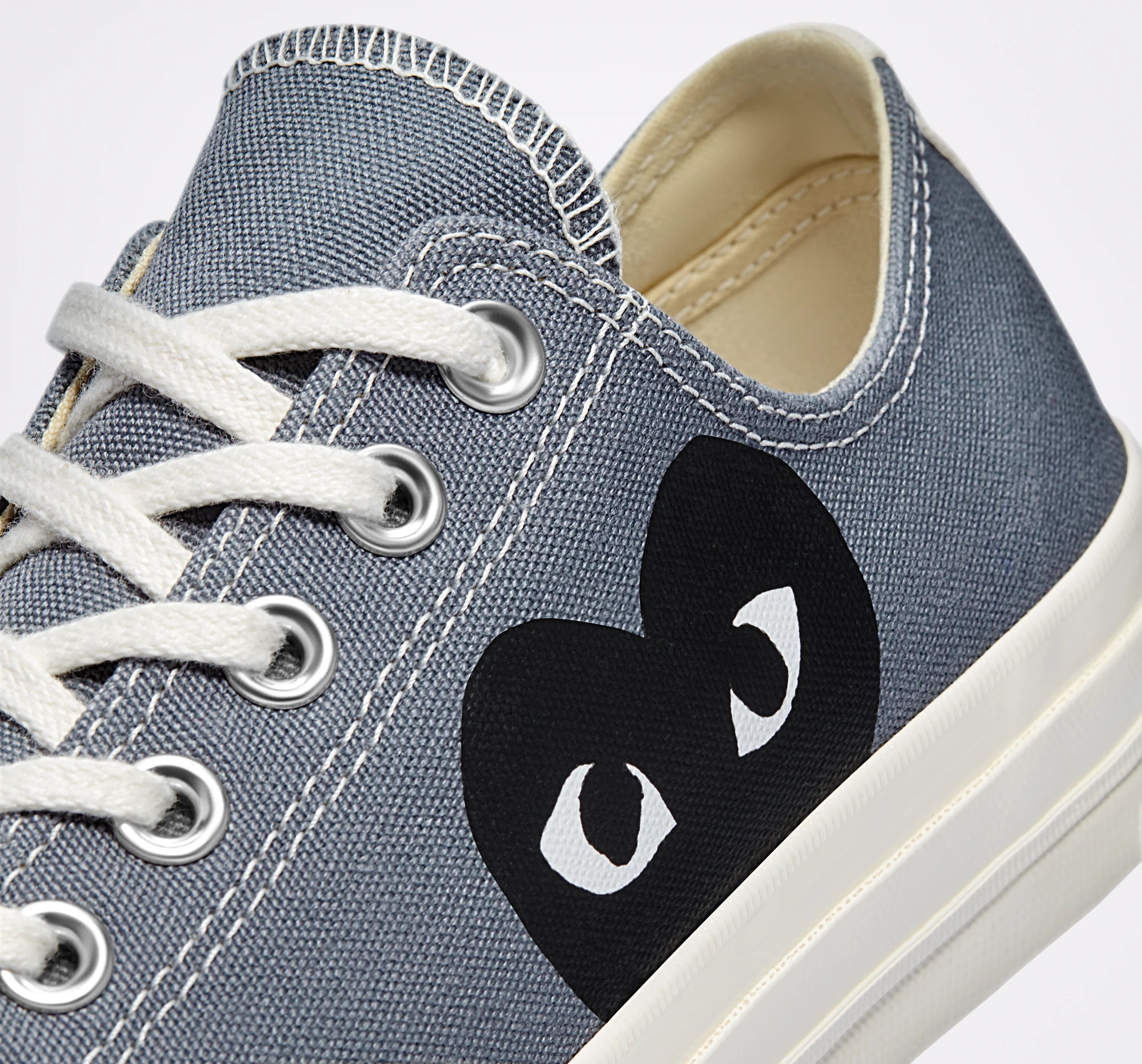 Comme des Garcons Play x Converse Chuck 70 Low Grey - macro close-up of black heart with eyes logo on grey canvas with silver eyelets and white laces