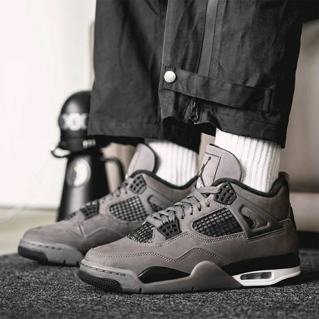 Jordan 4 Retro Cave Stone worn on feet with black cargo pants and white crew socks - on-foot lifestyle shot showing cave stone brown nubuck and Jumpman tongue branding