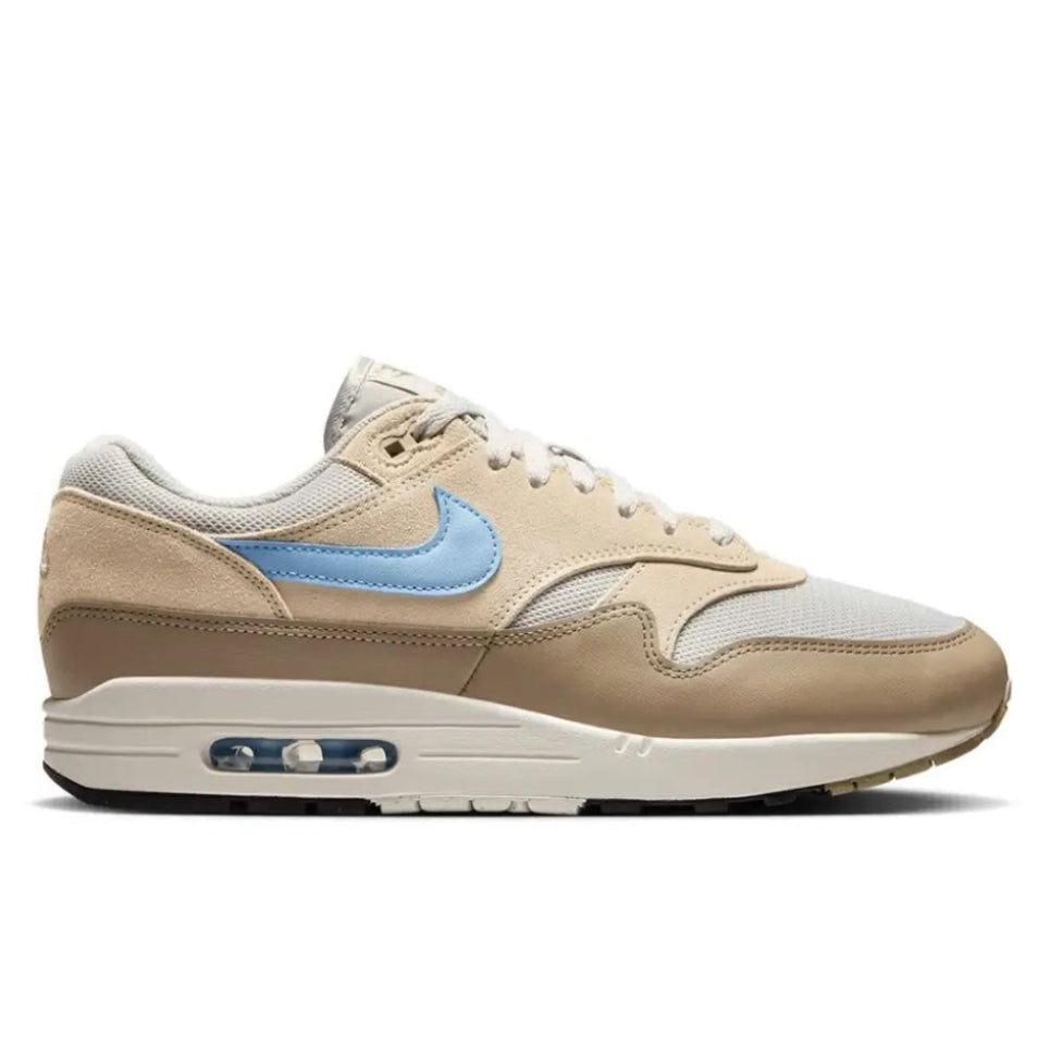 Nike Air Max 1 Light Bone Psychic Blue lateral side profile on white background showing light bone suede and leather upper, psychic blue Swoosh, and sail midsole with visible Air unit
