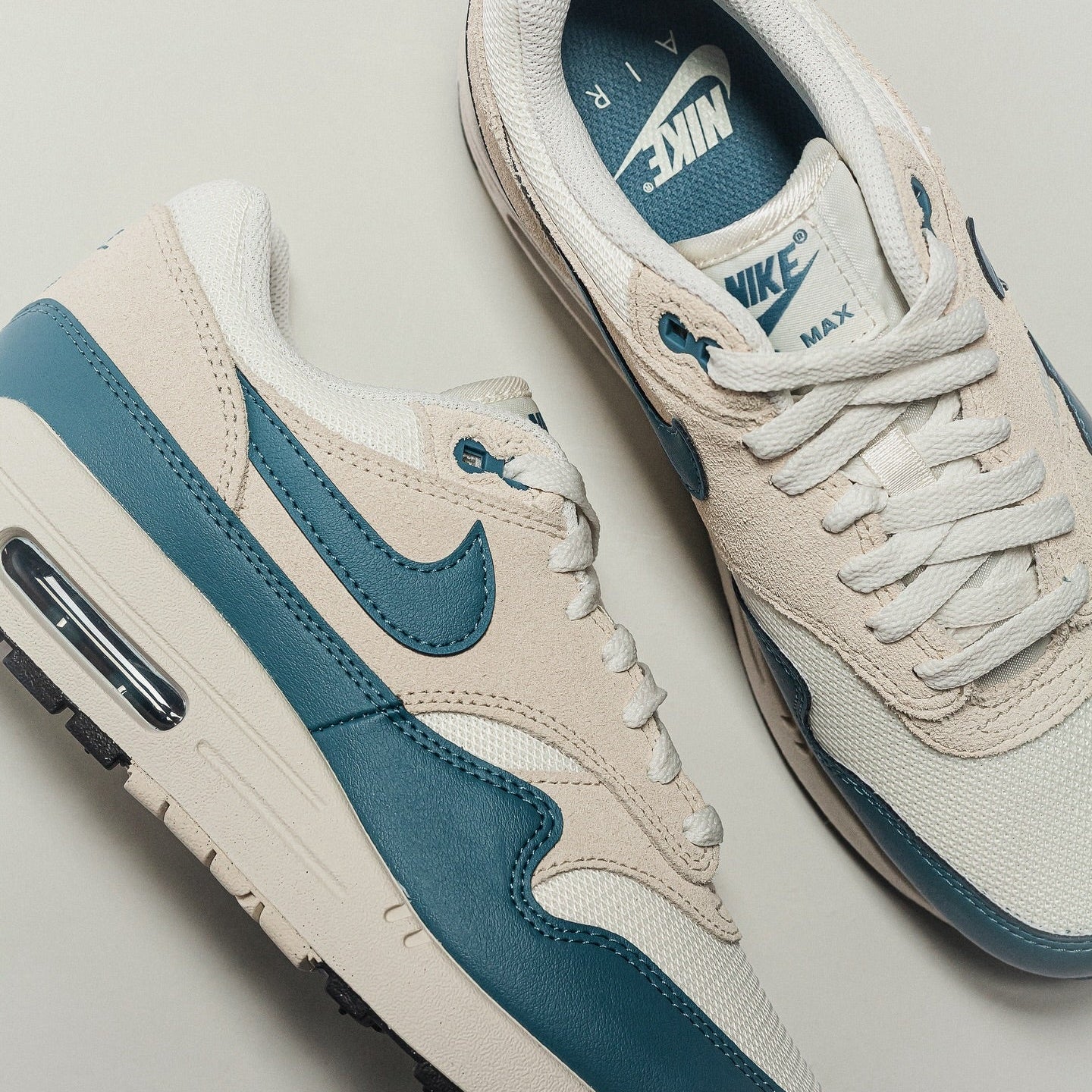 Nike Air Max 1 Soft Pearl Smokey Blue pair flat lay showing lateral Swoosh, suede overlays and teal insole branding