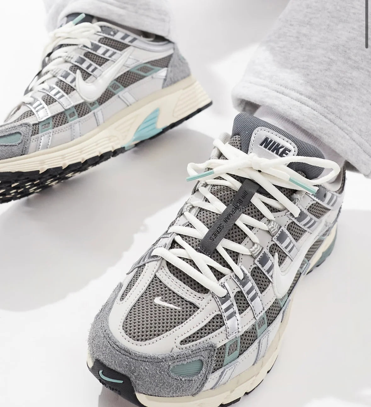 Nike P-6000 Flat Pewter on foot walking with grey sweatpants showing grey suede heel, metallic silver overlays, white Swoosh, and cream layered midsole
