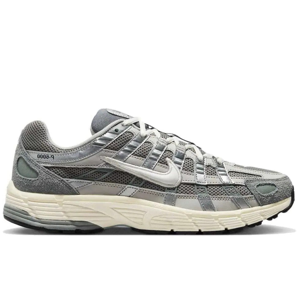 Nike P-6000 Flat Pewter lateral side profile on white background showing grey suede and mesh upper, metallic silver overlays, white Swoosh, and cream layered midsole