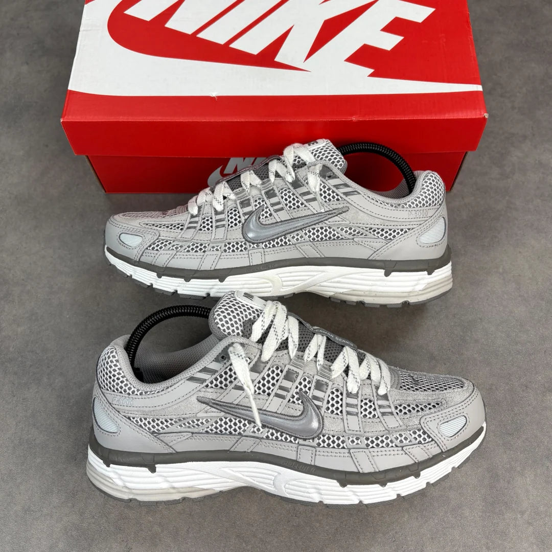 Nike P-6000 Light Iron Ore pair displayed with red Nike shoe box on concrete showing top-down view of grey mesh, silver Swoosh, and Bowerman Series tongue branding