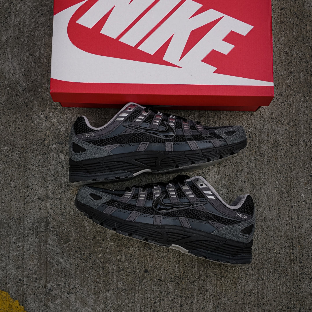 Nike P-6000 Suede Anthracite Metallic Silver pair top-down view next to red Nike shoe box on concrete showing anthracite suede overlays and black mesh