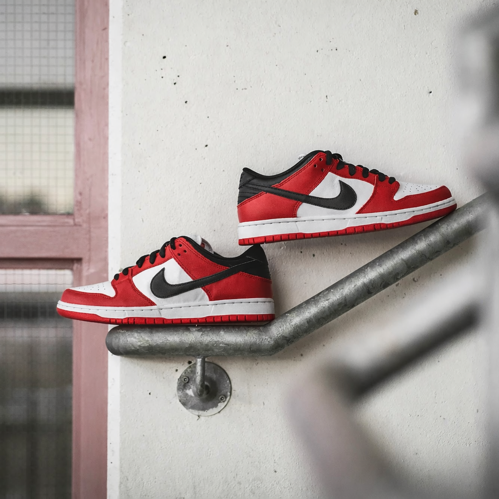 Nike SB Dunk Low J-Pack Chicago pair on railing editorial shot showing medial side with red overlays and red outsoleitorial Shot