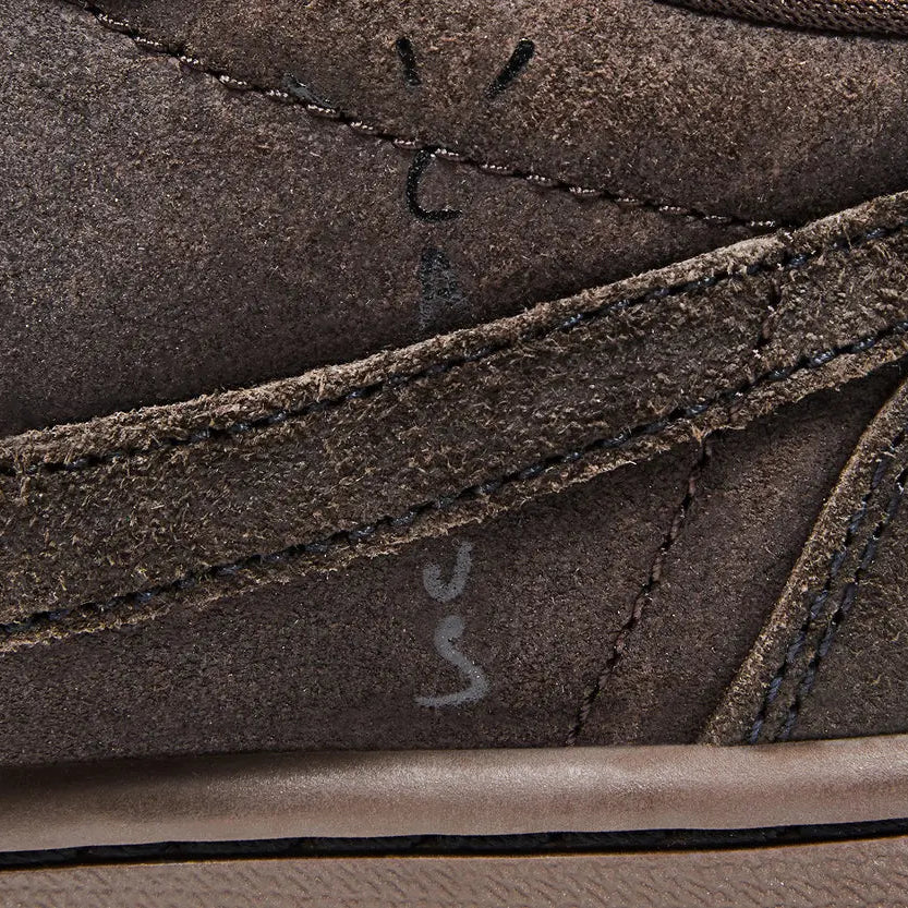 Close-up of Travis Scott x Air Jordan 1 Low OG SP Velvet Brown showing dark mocha suede texture, reverse Swoosh, and Cactus Jack branding on medial panel