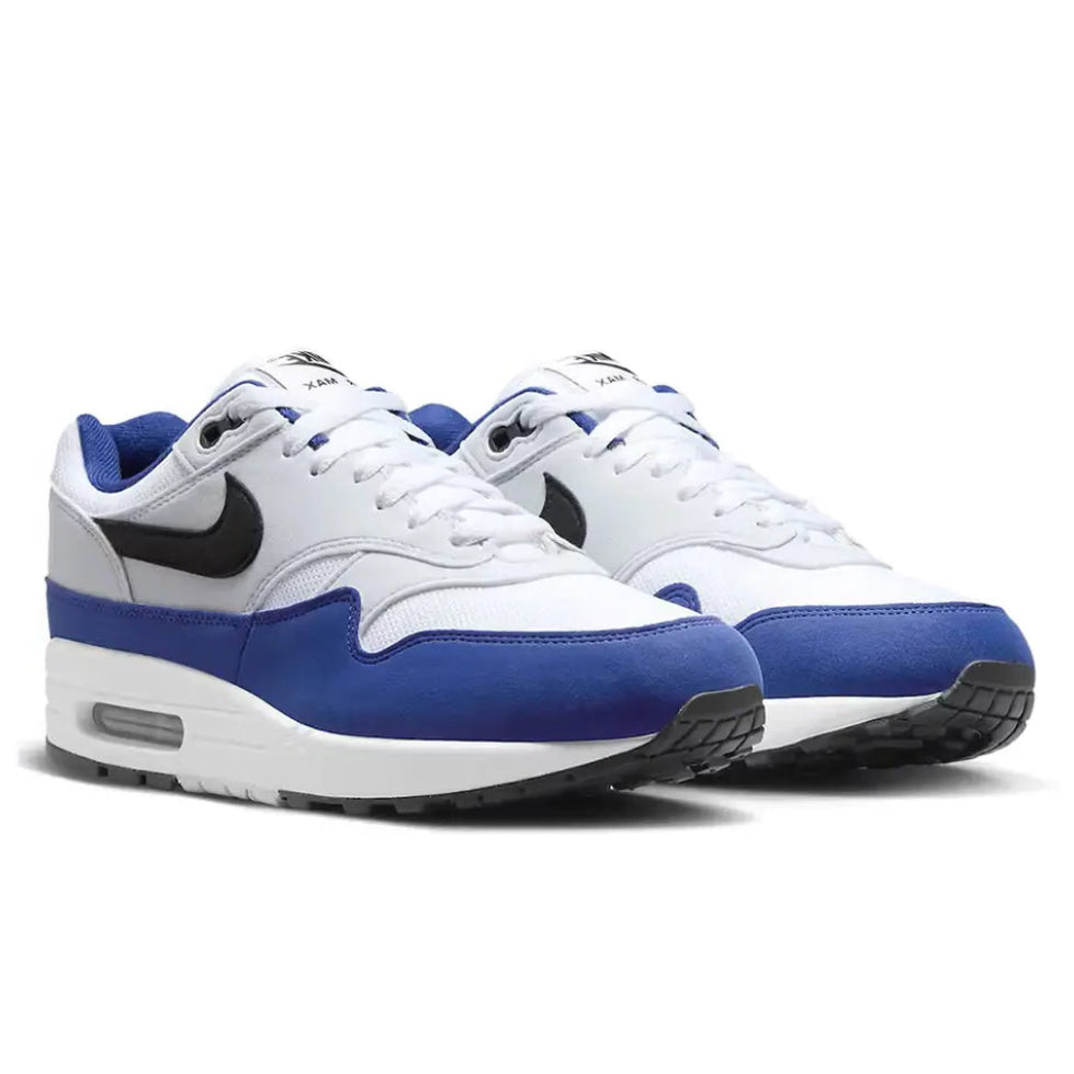 A pair of Nike Air Max 1 Deep Royal Blue trainers featuring white mesh, deep blue overlays, black Nike Swooshes and visible Air cushioning on a clean white background.
