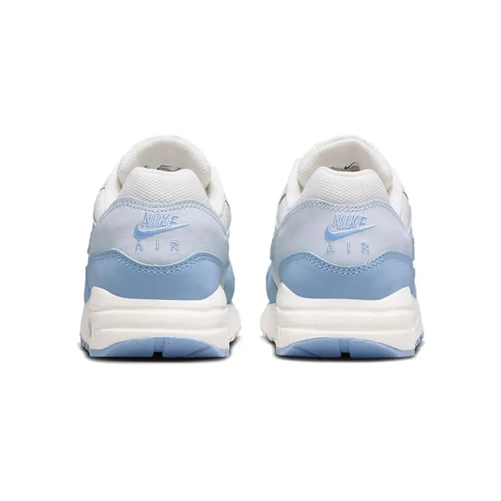 A rear view of the Nike Air Max 1 GS Sail Blue Tint trainers, showing the structured heel, pastel blue overlays and classic white midsole on a clean white background.
