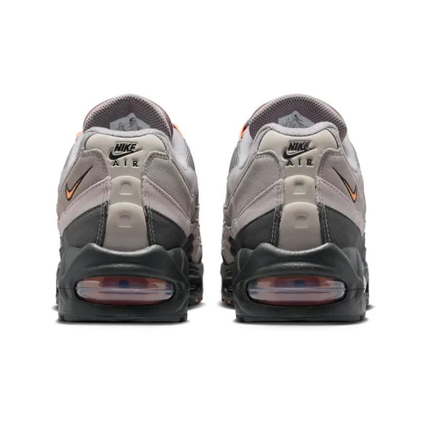 A rear view of the Nike Air Max 95 OG Big Bubble Bright Mandarin trainers, showing the structured heel, dark tonal construction, Bright Mandarin accents and visible Air units on a clean white background.