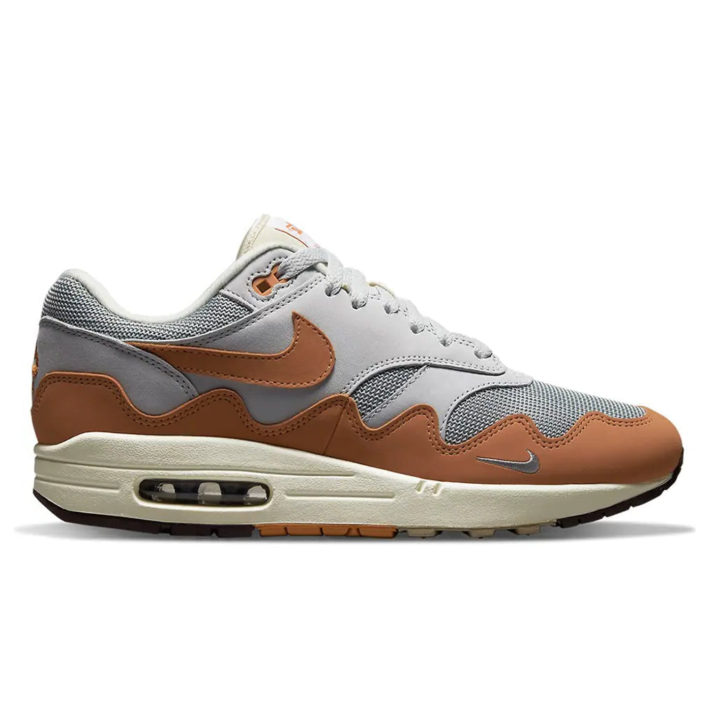 A side view of the Patta x Nike Air Max 1 Monarch showing the light grey mesh upper, orange Nike Swoosh and signature wave mudguard.