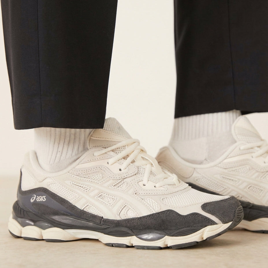 ASICS Gel-NYC Smoke Grey on feet close-up showing cream upper and dark grey suede with black trousers