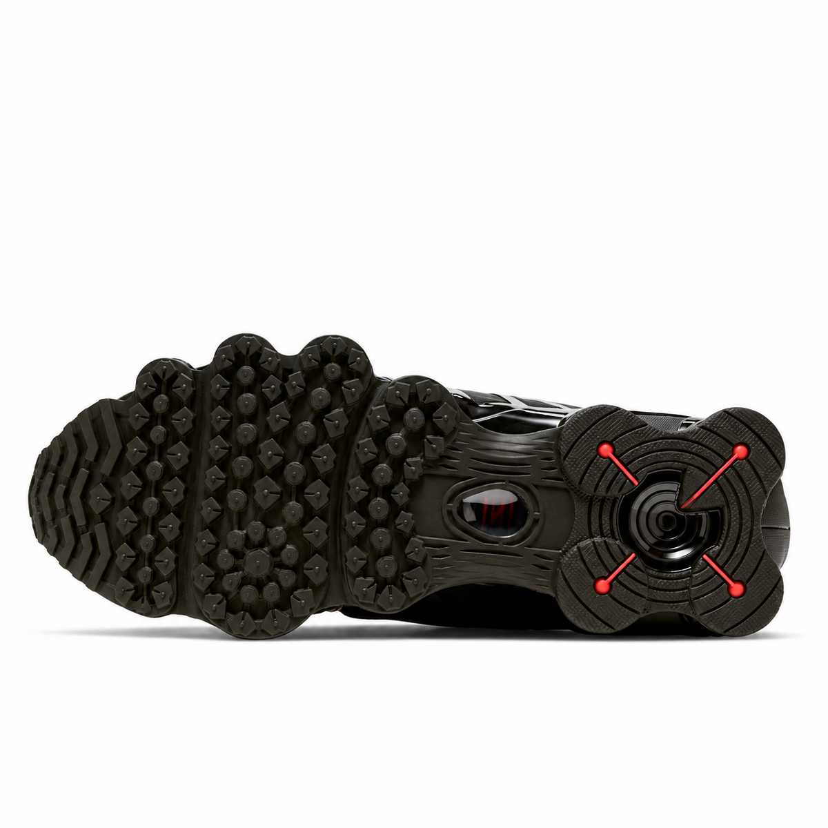 A close-up of a black athletic shoe's sole, showing a complex tread pattern and a rear heel design with red accent lines on a white background.