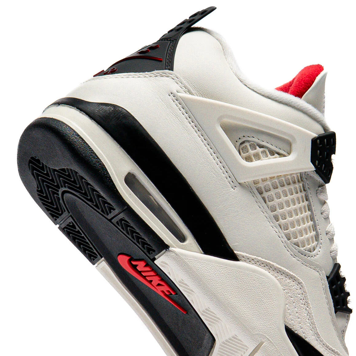Air Jordan 4 Flight Club angled close-up showing black outsole with red Nike branding, visible Air unit in heel, red inner lining, and sail leather upper