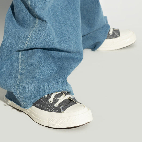 Comme des Garcons Play x Converse Chuck 70 Low Grey worn on feet with wide-leg blue jeans - close-up on-foot shot