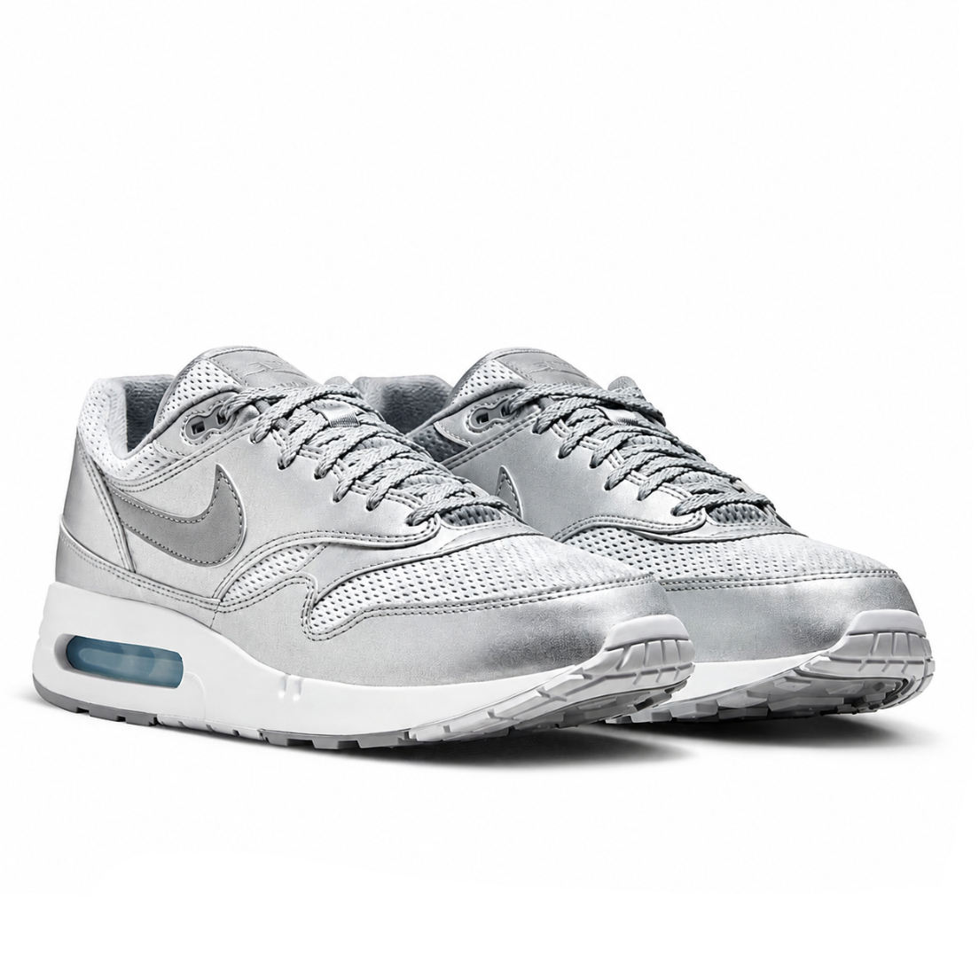 A pair of Nike Air Max sneakers in metallic silver and white, featuring a mesh and synthetic leather upper, gray laces, and a visible translucent air cushion unit in the heel.