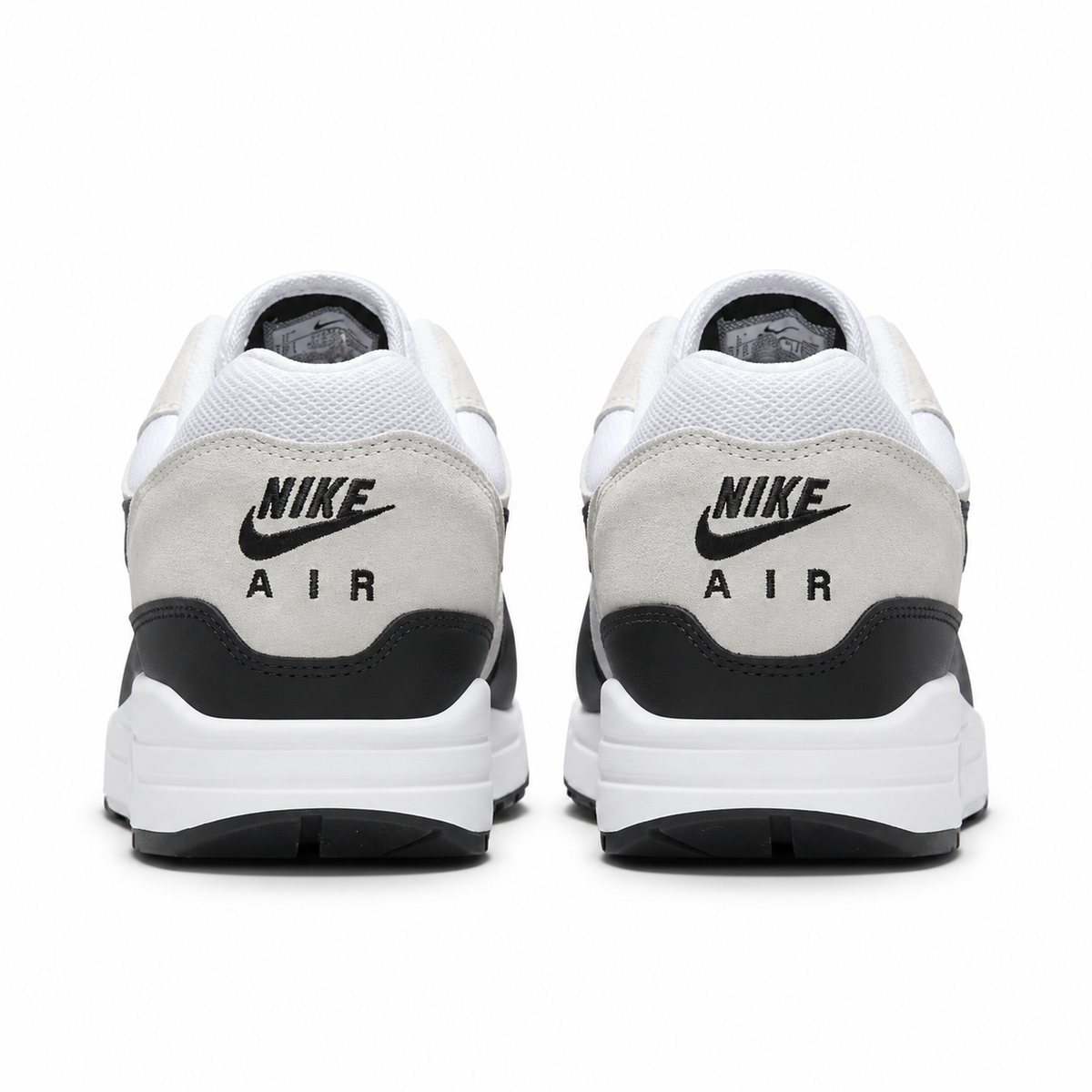 A rear view of the Nike Air Max 1 Essential Summit White Black trainers, showing the tan heel panel, black Nike Air branding and clean neutral colour palette.