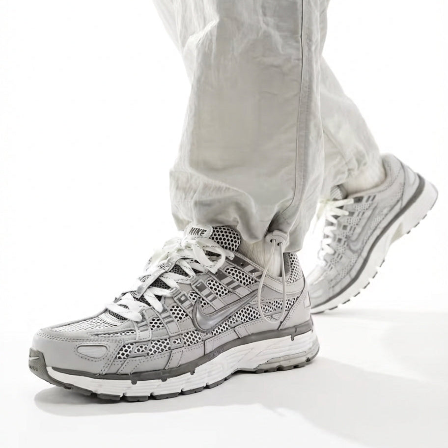 Nike P-6000 Light Iron Ore on foot walking with light grey trousers showing tonal grey leather and mesh upper, silver Swoosh, and white midsole