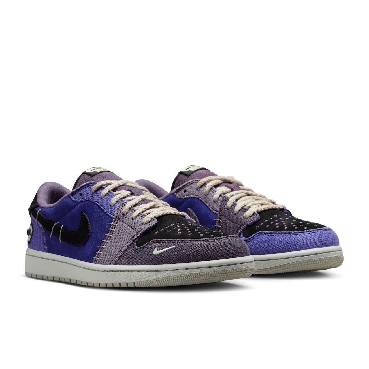 Zion Williamson x Air Jordan 1 Low OG Voodoo Alternate - front three-quarter pair view showing mismatched blue and purple canvas, black Swoosh, star-perforated toe box, skull detail and braided rope laces