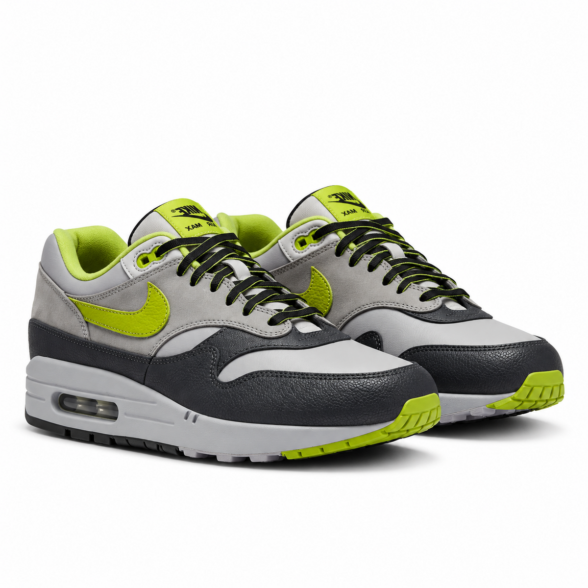 A pair of HUF x Nike Air Max 1 Grey Green trainers featuring light grey leather uppers, bright green Swooshes and textured mudguards on a clean white background.