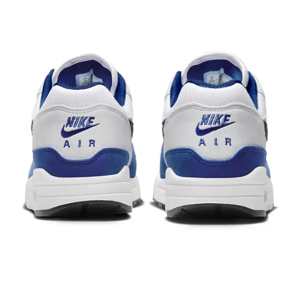 A rear view of the Nike Air Max 1 Deep Royal Blue trainers, showing the blue heel panel, black Nike Air branding and clean white midsole.