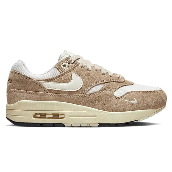 A side view of the Nike Air Max 1 Hangul Day trainer, showing the white mesh upper, brown suede mudguard, Sail Swoosh and classic visible Air midsole.