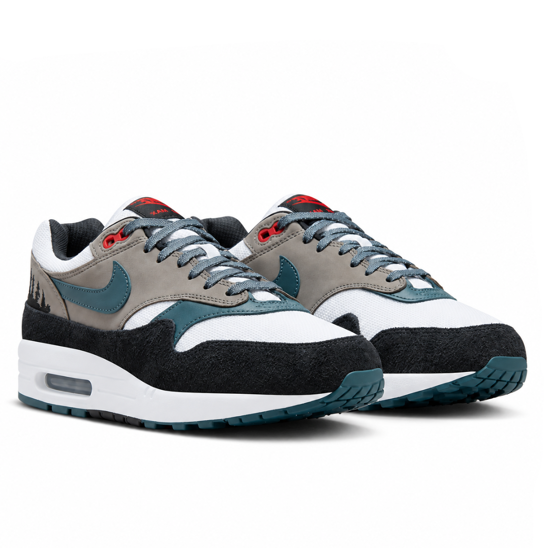 A pair of Nike Air Max 1 PRM QS Escape trainers featuring black suede mudguards, grey panels, green leather Swooshes, red accents and visible Air cushioning on a clean white background.