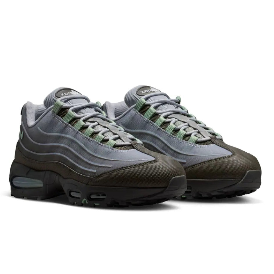 A pair of Nike Air Max 95 Medium Ash trainers featuring layered grey panels, metallic silver accents, breathable mesh and visible Nike Air cushioning on a clean white background.