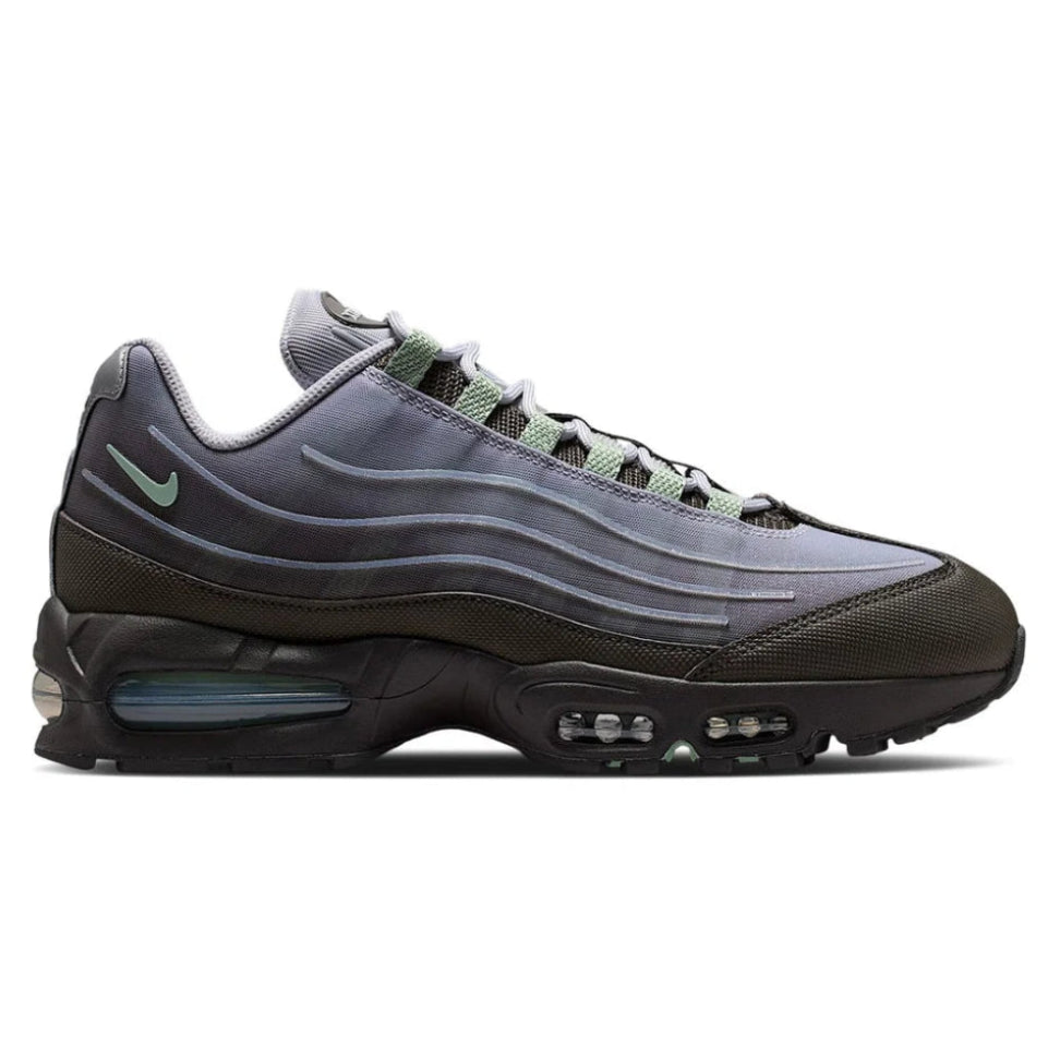 A side view of the Nike Air Max 95 Medium Ash trainer, showing the signature wavy grey panels, metallic silver detailing, small Nike Swoosh and visible Air cushioning.