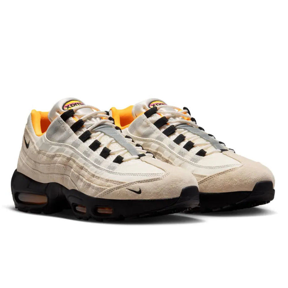 A pair of Nike SB Air Max 95 World Cup Pack Sail trainers featuring layered Sail panels, black detailing, bright orange accents and visible Max Air cushioning on a clean white background.
