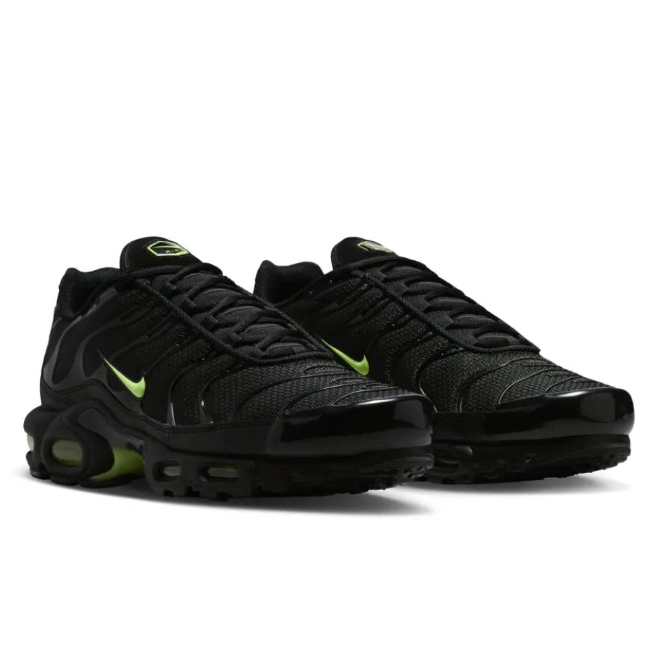 A pair of Nike Air Max Plus TN Black Volt Neon trainers featuring a black mesh upper, neon green accents, signature TPU wave overlays and visible Tuned Air cushioning on a clean white background.