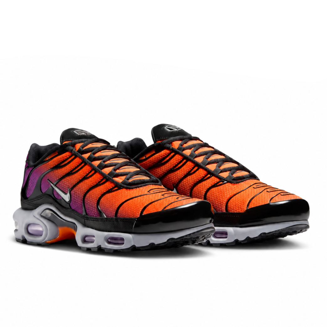A pair of Nike Air Max Plus TN Desert Sunset trainers featuring an orange-to-purple gradient mesh upper, black TPU wave overlays, metallic silver Swoosh detailing, a grey midsole and visible purple Tuned Air cushioning on a clean white background.