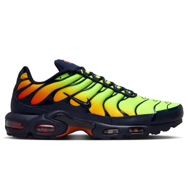 A Nike Air Max Plus sneaker in navy blue with a vibrant neon yellow, orange, and yellow gradient pattern on the upper, shown in a side profile on a white background.